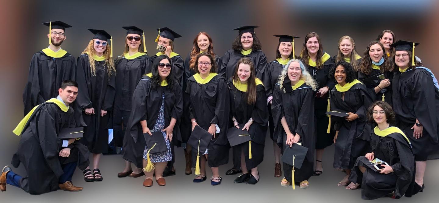 19个Sils毕业生穿着黑色长袍和黄色罩。